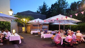 An outdoor dining area with tables and chairs, surrounded by trees and a building. - Stiftsberg Bildungs und Freizeitzentrum (Kyllburg)