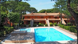 A resort with a swimming pool, a covered patio, and a building with a tiled roof. - Beautiful apartment for 6 people with A/C, pool, WIFI, TV, balcony and pets allowed (San Michele Al Tagliamento)