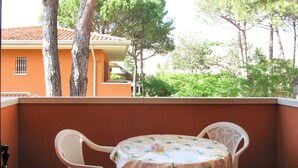 A balcony with a table and chairs, overlooking a residential area with trees and a building. - Beautiful apartment for 6 people with A/C, pool, WIFI, TV, balcony and pets allowed (San Michele Al Tagliamento)