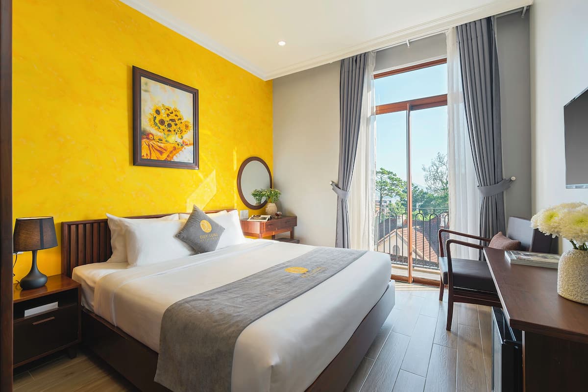 Ein Hotelzimmer mit einem großen Bett, einem Schreibtisch und Blick ins Freie.