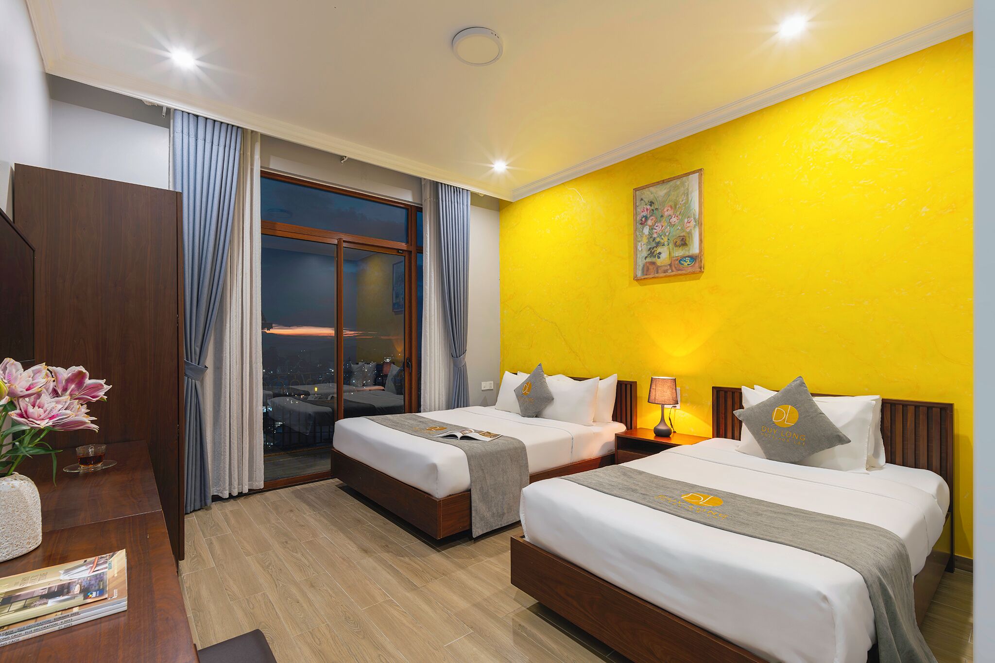 A hotel room with two beds, a desk, and a window with curtains.