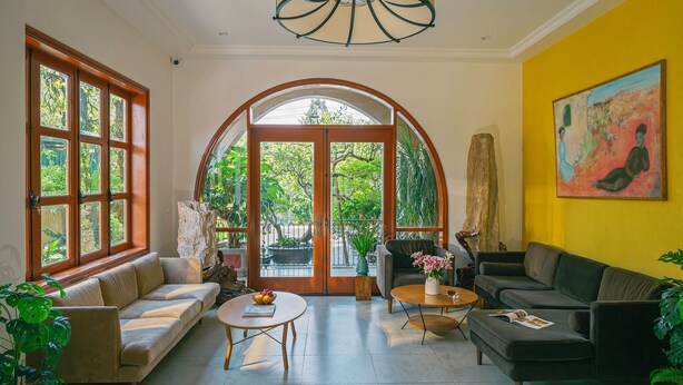 A spacious living room with a sofa, coffee table, and armchairs, large windows, and a painting on the wall. - Duy Long Hotel (Xuan Huong - Da Lat)