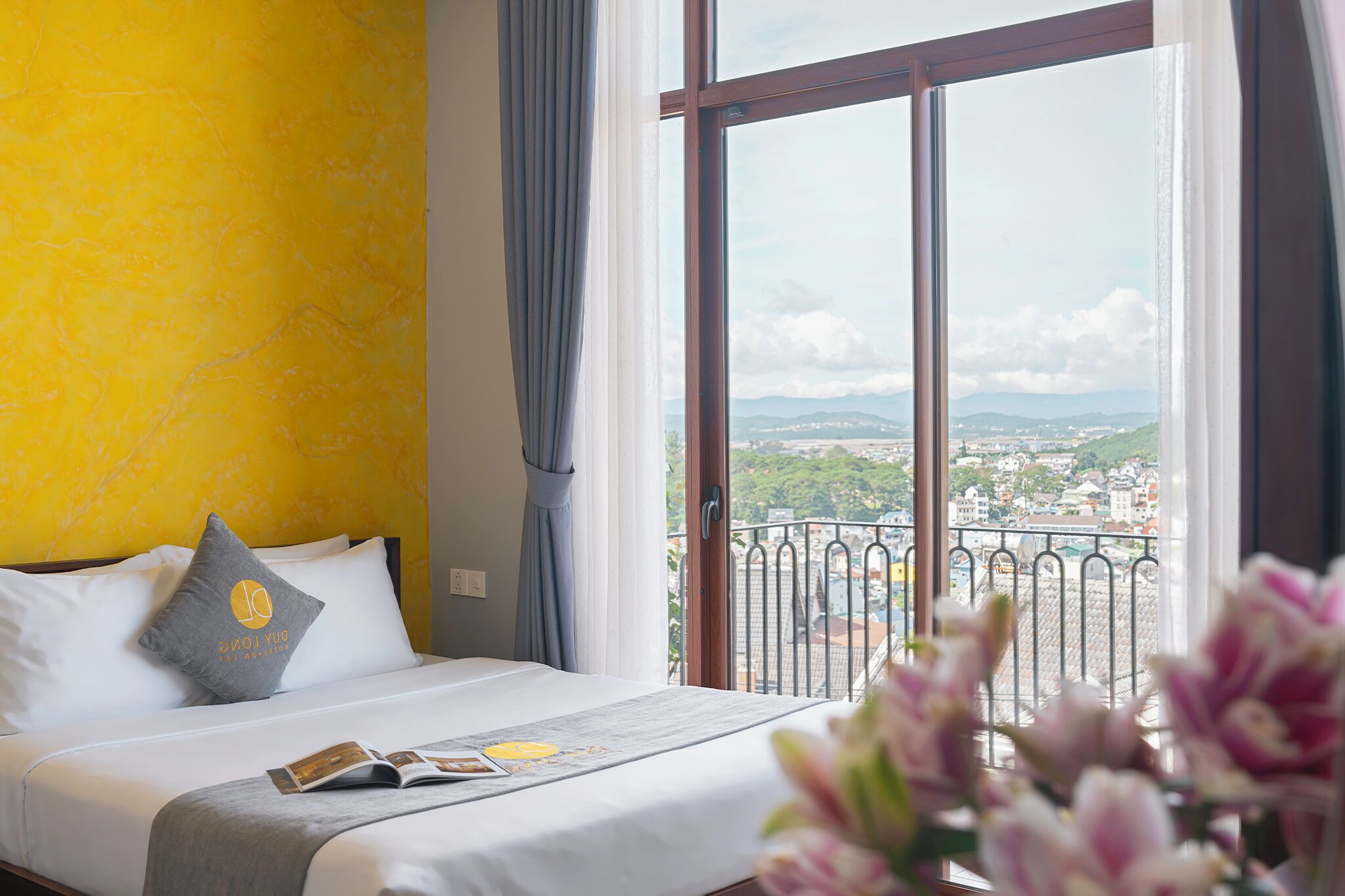 Una habitación de hotel con cama, ventana y vista panorámica de la ciudad, además de una cortina.
