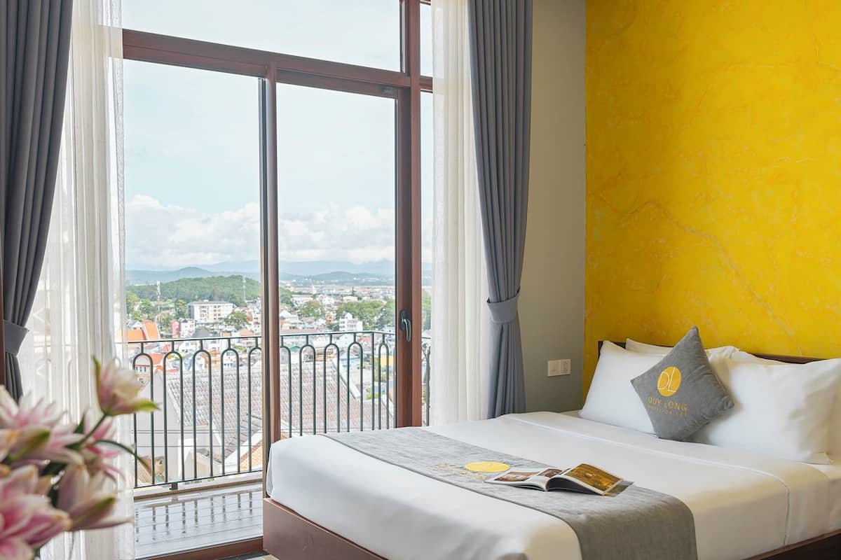 Ein Hotelzimmer mit Bett, Stadtblick und Balkon.