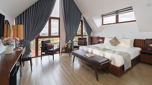A modern bedroom with a large bed, a desk, a chair, and a small table. - Duy Long Hotel (Xuan Huong - Da Lat)