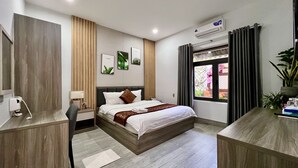 Habitación de hotel moderna con cama, mesita de noche, lámpara y vistas al exterior a través de una ventana.