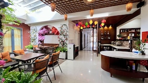 Un moderno vestíbulo de hotel con una zona de comedor, una recepción y una cocina a la vista.