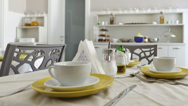 A dining area with a table set for two, featuring yellow plates and white cups. - B&B Mamma Carolina (Sanarica)