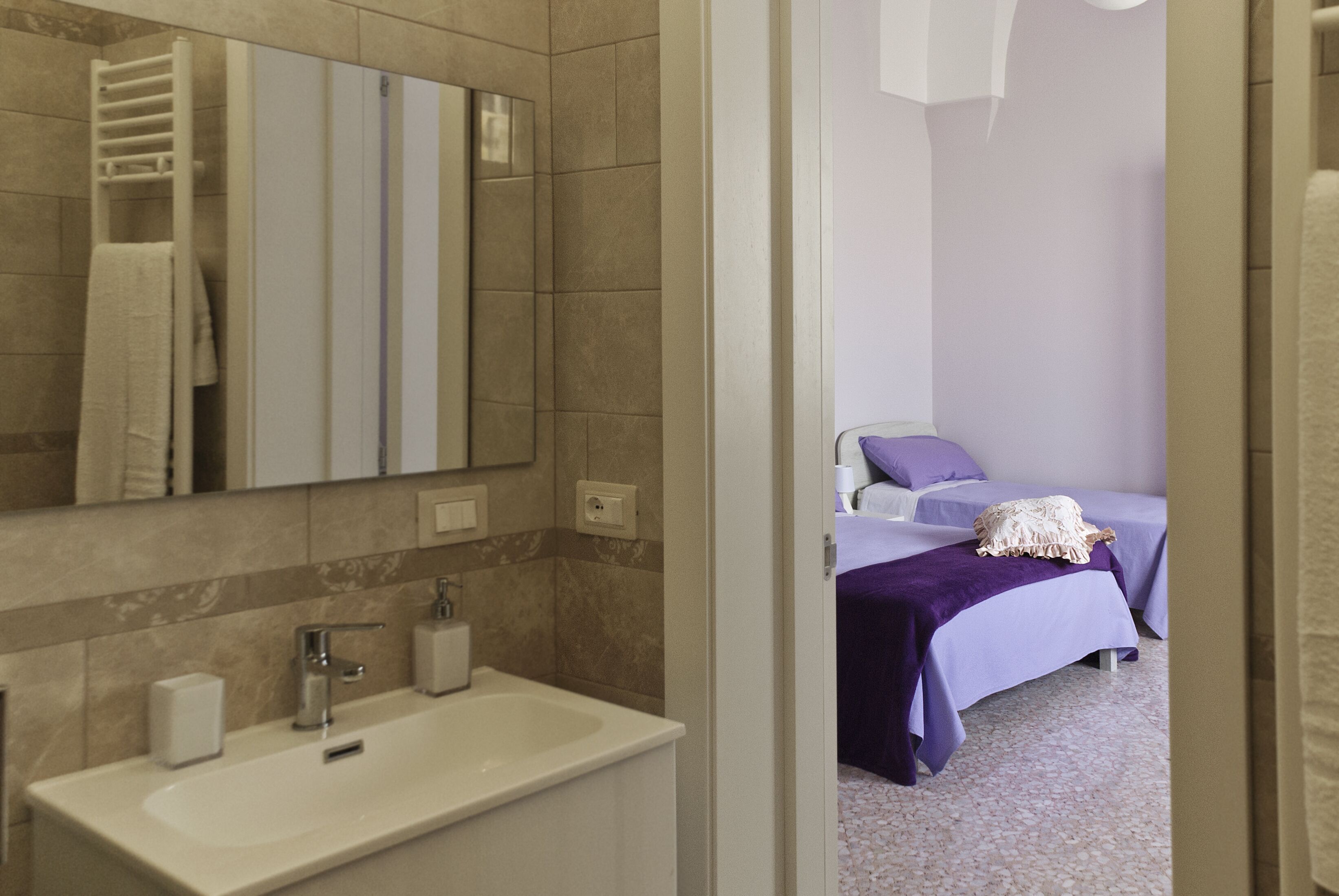 A bathroom with a sink, mirror, and towel rack.
