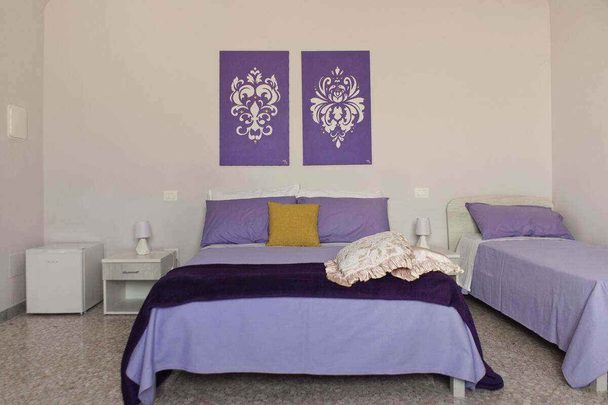 Un dormitorio con dos camas, una mesita de noche y una lámpara de pared.