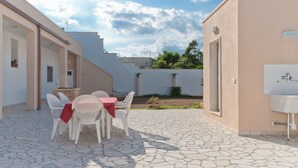 A patio with a table and chairs, a sink, and a small garden area. - B&B Mamma Carolina (Sanarica)