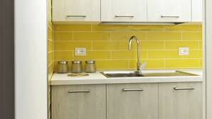 A kitchen with light wood cabinets, a stainless steel sink, and yellow tiles. - B&B Mamma Carolina (Sanarica)