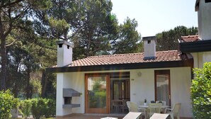 A two-story house with a tiled roof, a patio with outdoor furniture, and a well-maintained lawn. - Beautiful apartment in villa for 8 guests with A/C, pool, TV, terrace and pets allowed (San Michele Al Tagliamento)