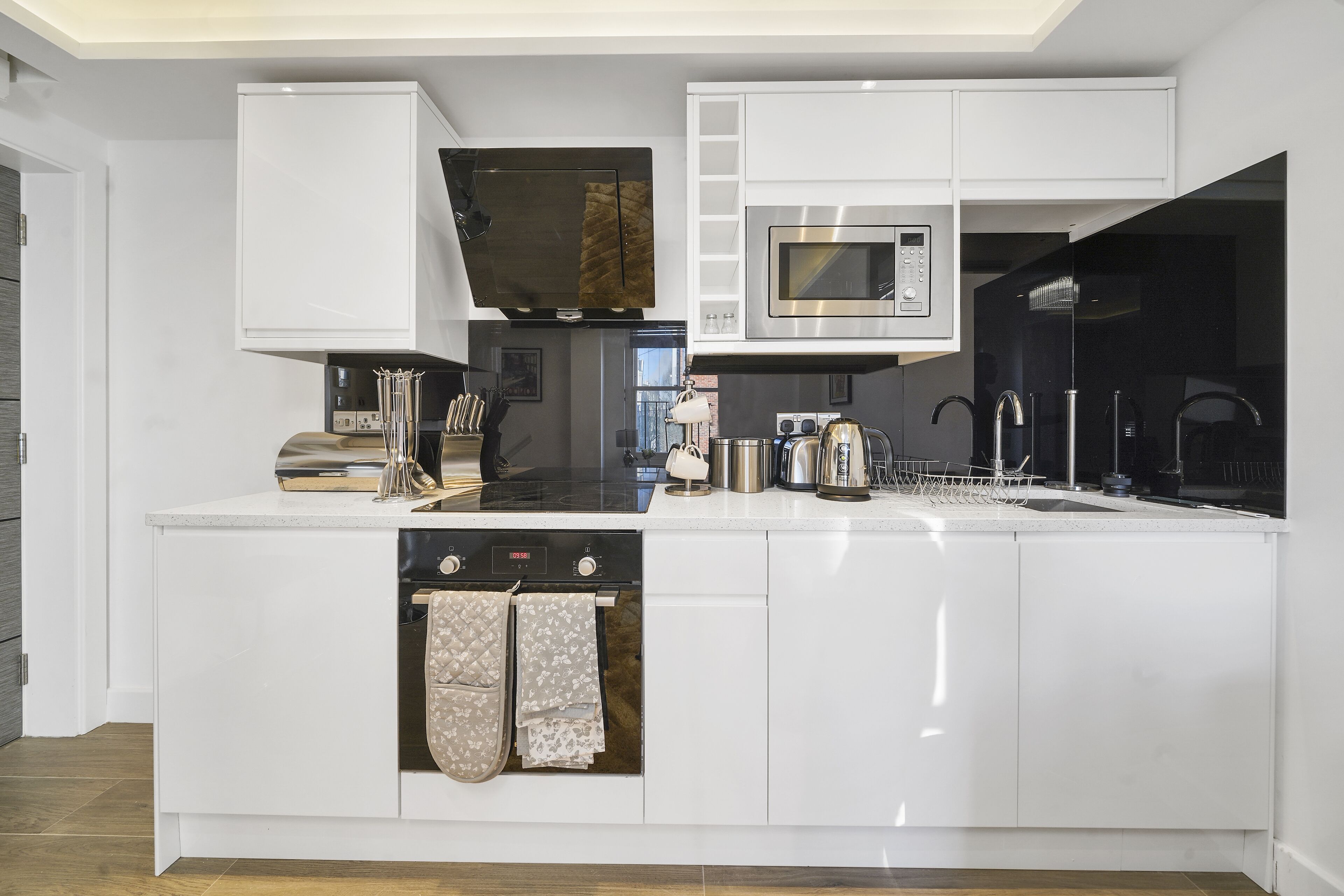 A modern kitchen with white cabinetry, a built-in microwave, a stove, and a dishwasher.