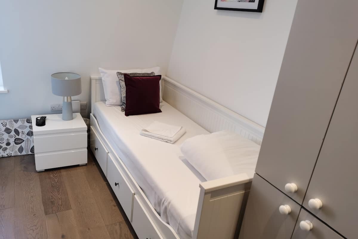 A neatly arranged bedroom with a bed, bedside table, lamp, and a wardrobe.
