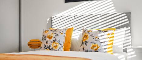 A bed with floral-patterned pillows and a striped headboard.
