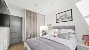 Un dormitorio moderno con cama, mesita de noche y un amplio ventanal.