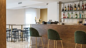 A bar area with a marble countertop, green bar stools, and a variety of liquor bottles. - Grand Hotel Serapide (Pozzuoli)