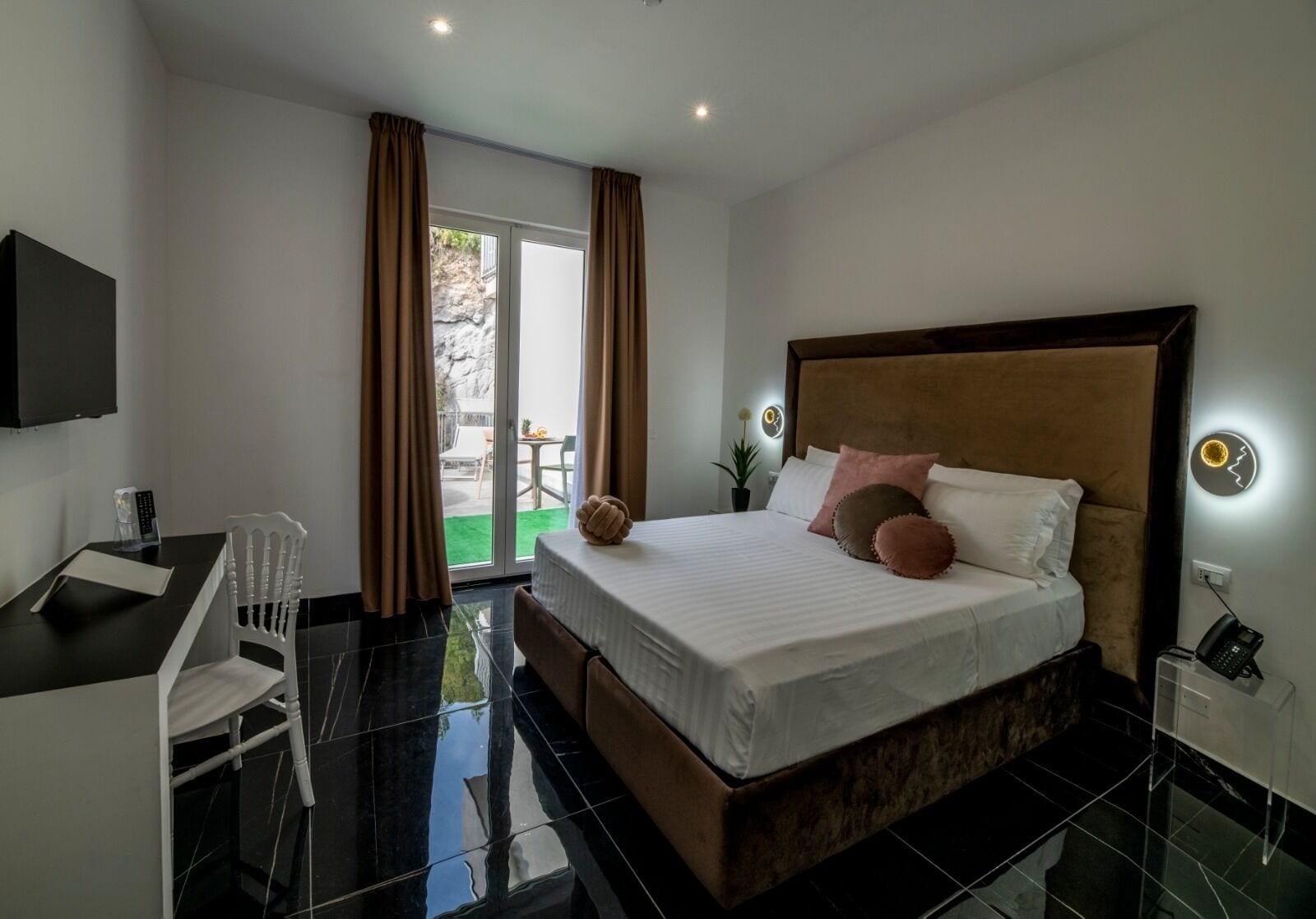 A modern hotel room with a large bed, a desk, and a TV.