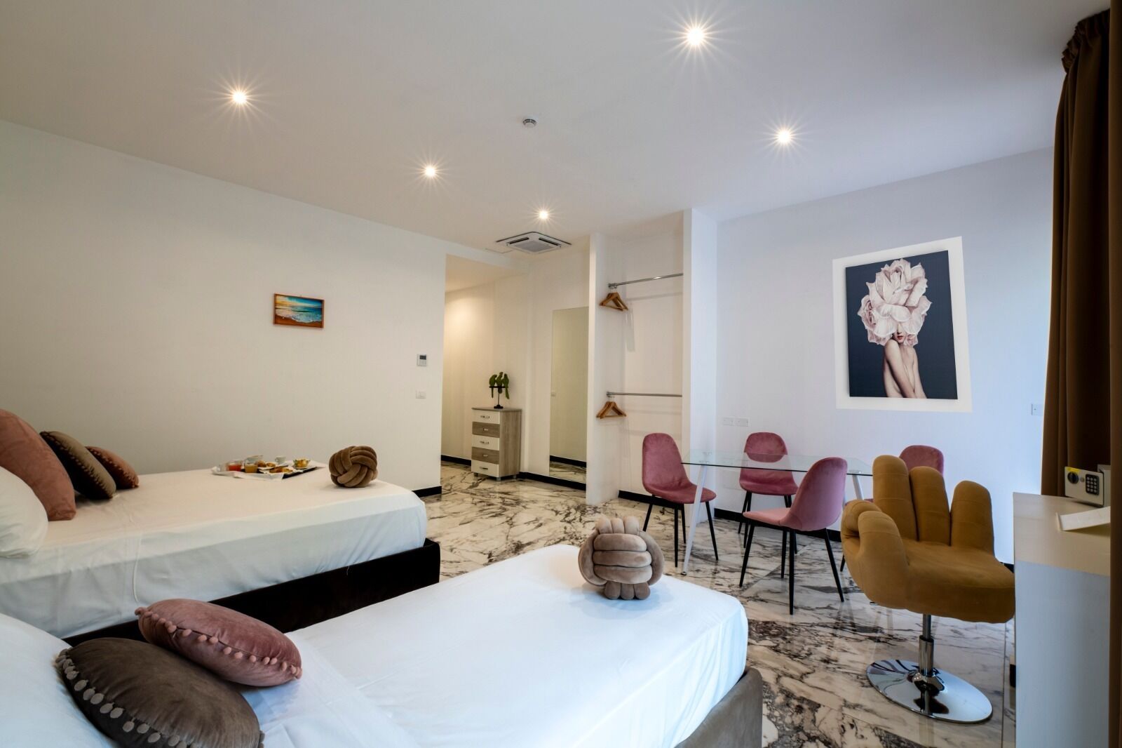 A hotel room with two beds, a dining area with chairs, and a small table.