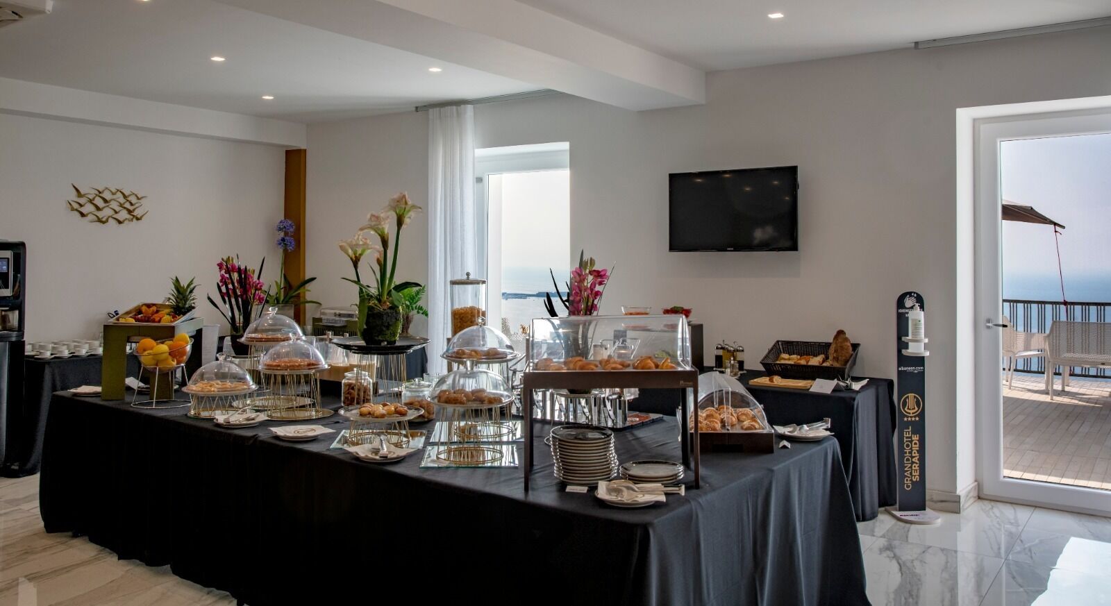 A buffet setup with various food items and a television on the wall.