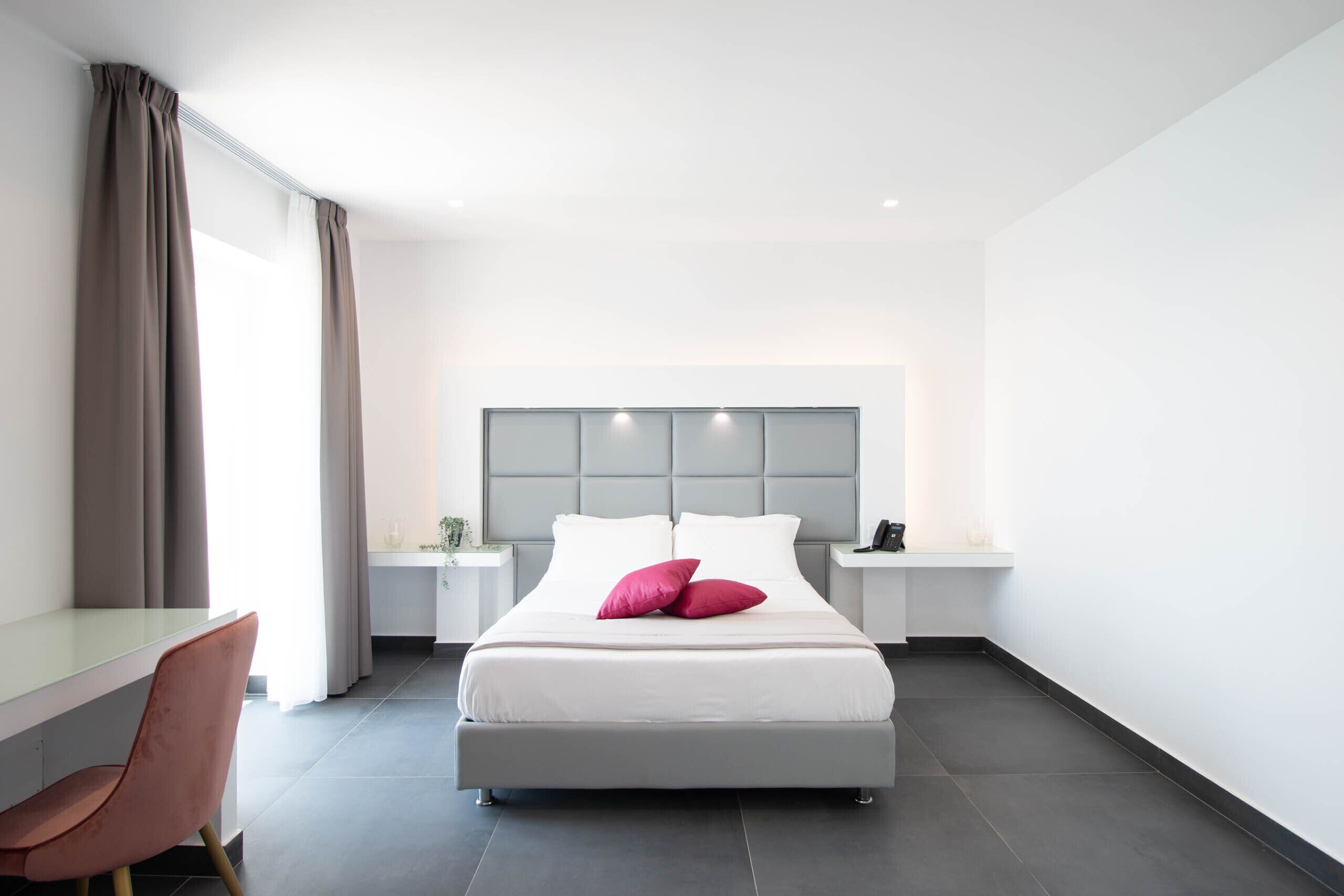 Une chambre d’hôtel moderne, dotée d’un grand lit, d’un bureau et d’une chaise.