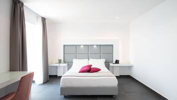 Une chambre d’hôtel moderne, dotée d’un grand lit, d’un bureau et d’une chaise.