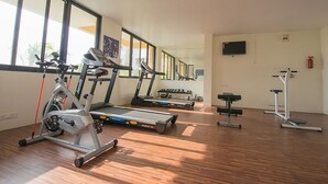 A gym with cardio machines, dumbbells, and a bench press.