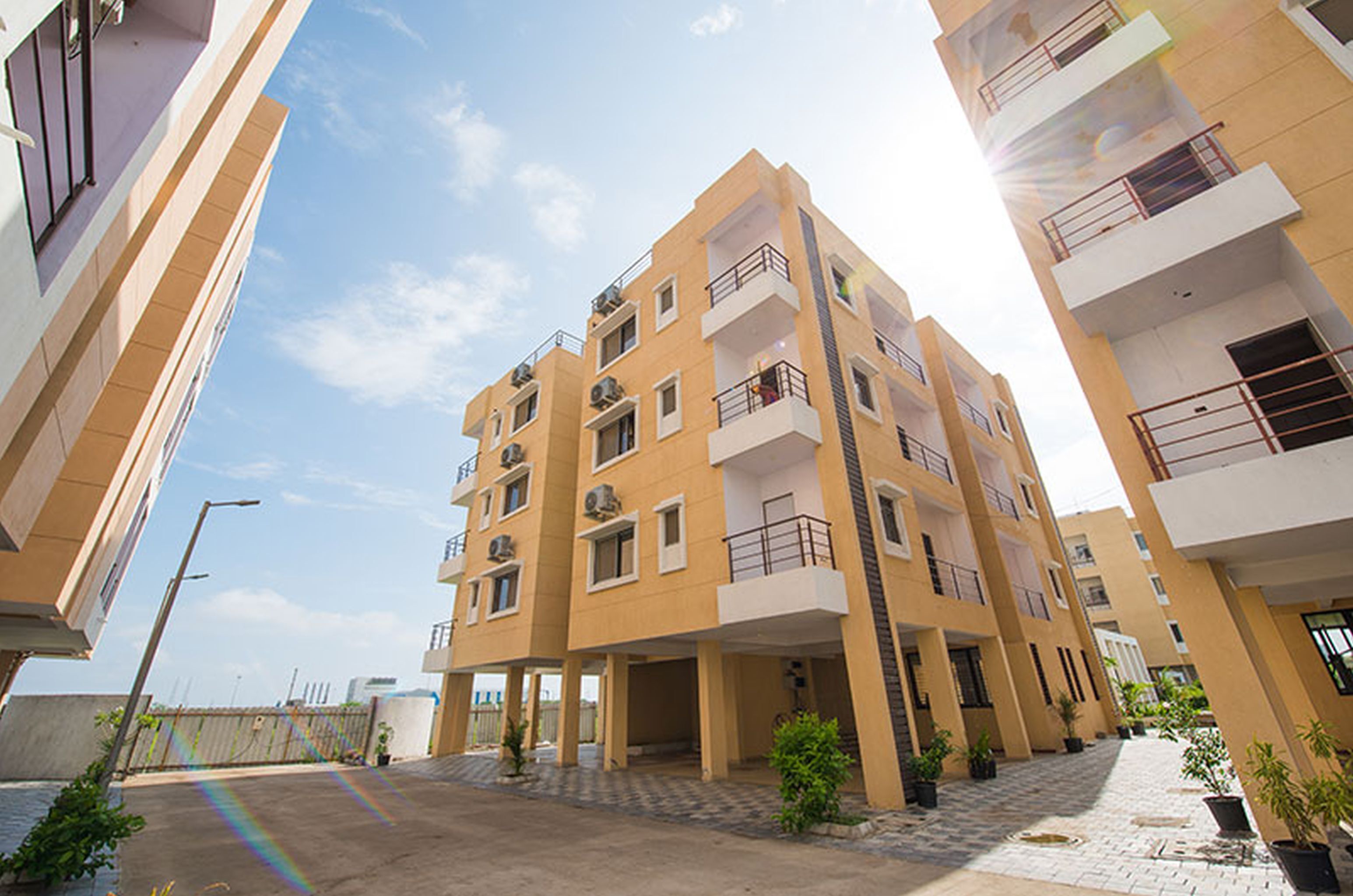 Un edificio residencial de varios pisos con balcones, un patio empedrado y plantas en macetas.