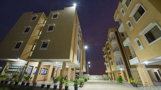 A multi-story residential building with a central courtyard, potted plants, and a well-lit entrance.