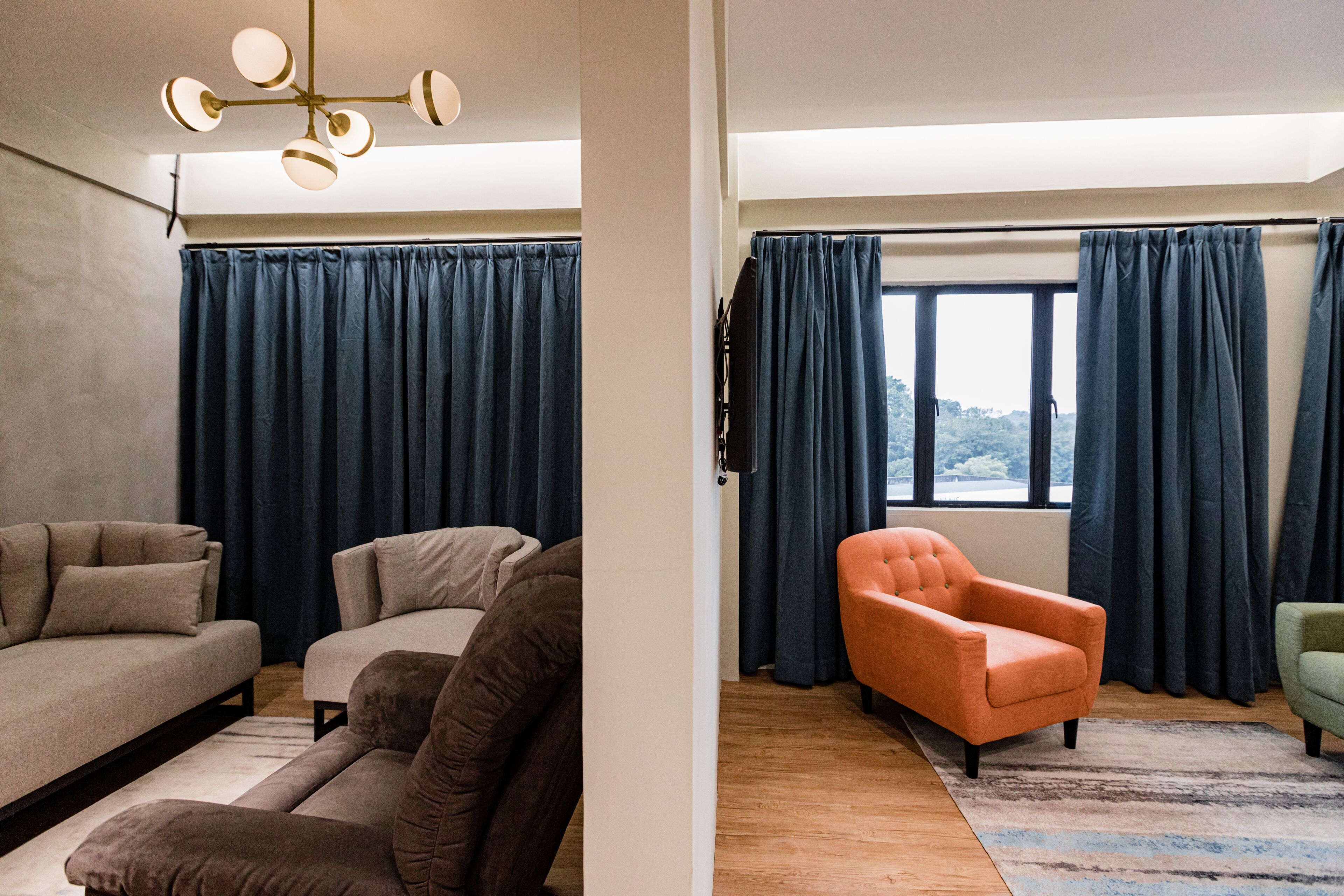 A modern living room with a sofa set, a coffee table, and a large window with curtains.