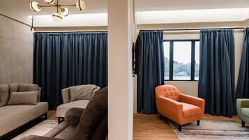 A modern living room with a sofa set, a coffee table, and a large window with curtains.