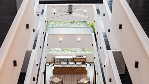 Een meerlaags atrium met een centraal bargedeelte, zitplaatsen en uitzicht op groen door de hogere niveaus.