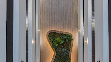 Stroll through the serene garden area surrounded by lush greenery and a brick pathway.