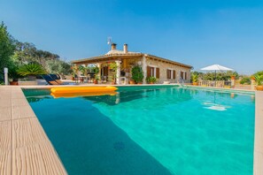 A pool area with a wooden deck, lounge chairs, and a building with a tiled roof. - SA ROTA Finca for 6 people in Ariany with pool (Ariany)