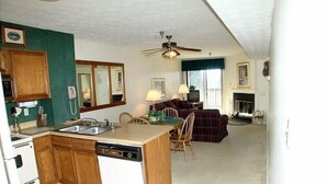 A compact kitchen with a dishwasher, wooden cabinets, and a dining area with a table and chairs.