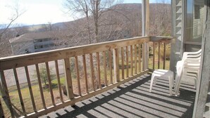 A wooden deck with a view of a house and hills in the background.