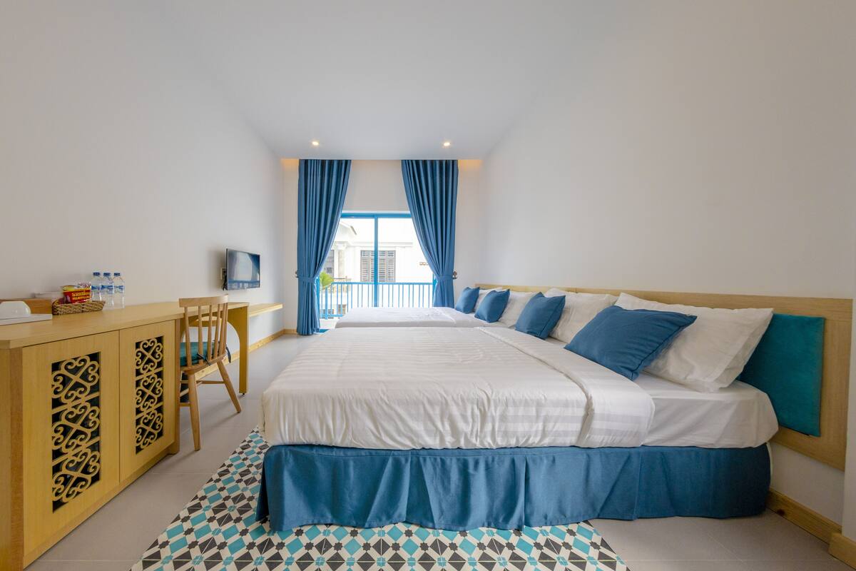 A hotel room with two beds, a desk, and a chair.