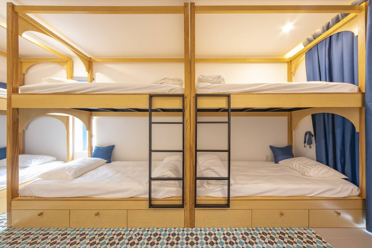 A bunk bed room with a ladder, wooden frame, and a patterned floor.