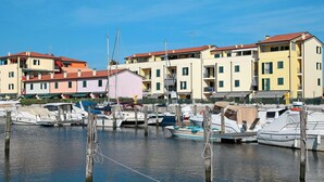 A marina with boats docked, surrounded by multi-story buildings with balconies.