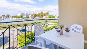 A balcony with a table and chairs, overlooking a marina with boats and buildings.