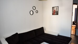 Un saló modern amb un sofà seccional negre, un element decoratiu blanc i un quadre amb una cabina telefònica vermella.