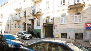 Edifici de diverses plantes amb entrada a la planta baixa, escala que condueix a un pis superior i un senyal visible que indica una zona d'aparcament.