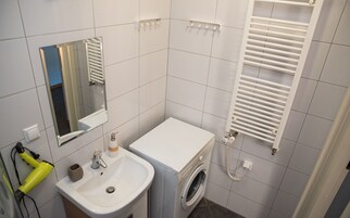 Un baño pequeño con lavamanos, espejo y lavadora.