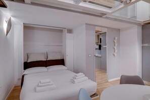 A modern hotel room with a bed, a seating area, and a view of the kitchen. - Flatty Apartments - Volta (Milan)