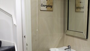 Un baño con un lavamanos blanco, un espejo y un letrero que dice 'Lough Everyday'.