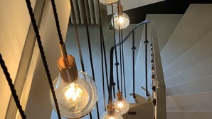 A staircase with a modern design, featuring a series of hanging light fixtures with clear glass bulbs and copper accents. - Casa Vinitoscani (Perroy)