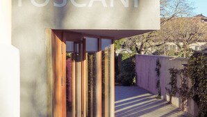 A modern building entrance with a wooden door and a clear view of the surrounding area. - Casa Vinitoscani (Perroy)