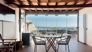 An outdoor seating area with a table and chairs, a view of the sea, and a stone wall. - Lagos Uptown Bed & Breakfast (Lagos)