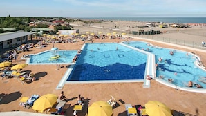 A large outdoor swimming pool with multiple lanes, surrounded by sun loungers and umbrellas. - Lovely apartment in villa for 5 guests with A/C, pool, WIFI, TV and terrace (Rosolina)